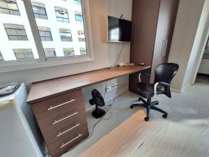 un ufficio con scrivania, sedia e televisore di LK Estoril 3 a Belo Horizonte