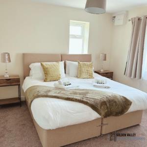 una camera da letto con un letto grande con lenzuola e cuscini bianchi di White Jasmine in Stroud a Dudbridge