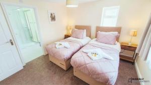 2 posti letto in una camera con lenzuola e asciugamani rosa di White Jasmine in Stroud a Dudbridge Altre 3 foto
