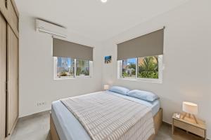 a white bedroom with a bed and two windows at Apartement Ocean Hibiscus, Punta Azul Ocean Resort, Westpunt in Lagun +41 photos