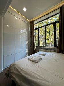 a bedroom with a white bed with a large window at Fairytale Apartment in Aghk'ilisa