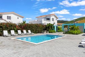 a villa with a swimming pool in front of a house at Ocean Hibiscus, Punta Azul, Curacao in Lagun