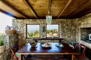 una sala da pranzo con tavolo in legno e parete in pietra di Villa Erika ad Agios Ioannis