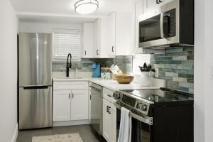 a kitchen with white cabinets and a stainless steel refrigerator at Beachside Bliss - Beach House Unit 2 in Jacksonville Beach