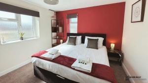 een slaapkamer met een groot bed met een rode muur bij Modern & Spacious Flat with Balcony Views in Stroud