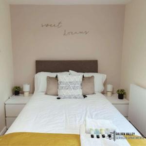 een slaapkamer met een groot bed met witte lakens en kussens bij Modern & Spacious Flat with Balcony Views in Stroud