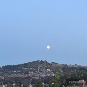 een vliegtuig dat over een stad vliegt op een heuvel bij Modern & Spacious Flat with Balcony Views in Stroud +2 foto's