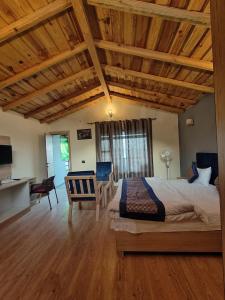 Un dormitorio con una cama grande y una mesa y sillas. en The woodpecker nest by lake & woods, en Rāmgarh