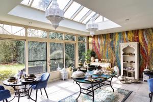 a conservatory with tables and chairs and windows at B&B 1001 nacht in Zonhoven