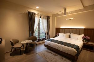 ein Schlafzimmer mit einem Bett und einem Tisch und einem Fenster in der Unterkunft Rosse Dale Suites and Hotel Coimbatore in Coimbatore + 51 Fotos