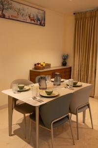 einen Tisch mit 2 Stühlen und einen weißen Tisch mit Tellern in der Unterkunft Rosse Dale Suites and Hotel Coimbatore in Coimbatore