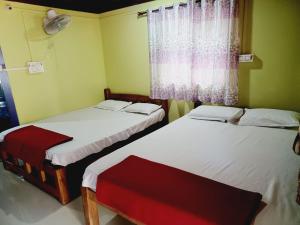 two beds in a small room with a window at Gokarna Royal Cottage in Gokarna