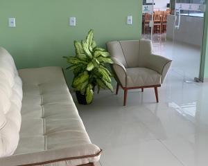 ein Wohnzimmer mit einem Sofa, einem Sessel und einer Pflanze in der Unterkunft Lençóis Barreirinhas in Barreirinhas