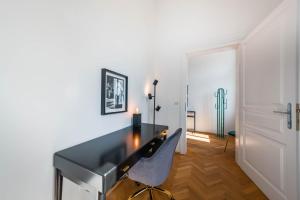 een zwart bureau in een witte kamer met een stoel bij Smile Apartments am Stadtpark in Krems an der Donau