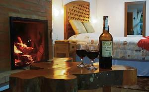een fles wijn en twee glazen op een tafel met open haard bij Chalés Colline Verte in Monte Verde