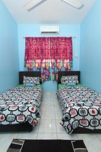 a room with two beds and a window at Noah's Homestay in Shah Alam