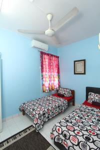 a room with two beds and a ceiling fan at Noah's Homestay in Shah Alam