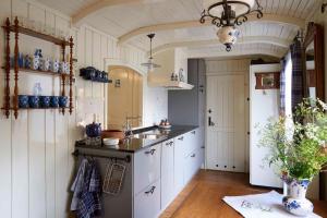 a kitchen with white cabinets and a sink at Pipowagen de Luxe, prive hottub en zwembad in Heythuysen
