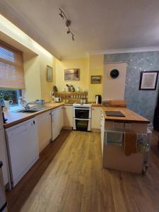 een grote keuken met witte apparatuur en houten vloeren bij Andreu Cottage in Callander +14 foto's