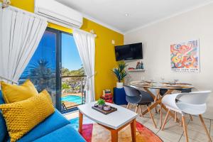 a living room with a blue couch and a table at Gordons Village View in Gordonʼs Bay