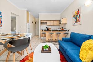 a living room with a blue couch and a kitchen at Gordons Village View in Gordonʼs Bay