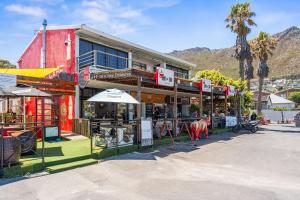 a group of buildings with tables and umbrellas on a street at Gordons Village View in Gordonʼs Bay