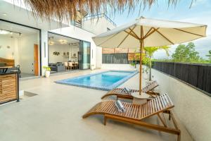 an umbrella and chairs next to a swimming pool at Shukty Villa Pandawa in Ungasan