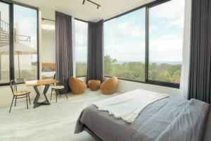 a bedroom with a bed and a desk and windows at Shukty Villa Pandawa in Ungasan +9 photos