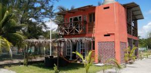 a red house with a palm tree in front of it at Casa Playa Linda VILLA LUA Tapachula in El Desengaño