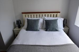 een slaapkamer met een wit bed met 2 kussens bij Govandale Seaviews in Kingarth