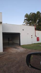 a white building with a garage and a palm tree at Stillus Private Motel in Alfenas