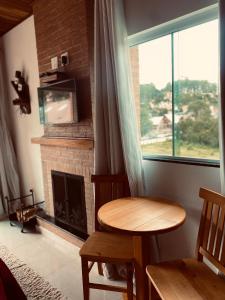 una sala de estar con una mesa y una chimenea en Pousada D'avilas, en Monte Verde