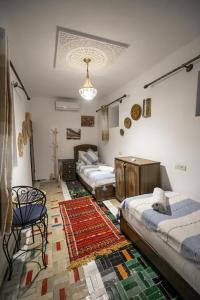 a room with four beds and a rug at Jnan Dar Sbil in Fès