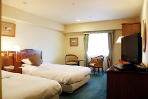 ein Hotelzimmer mit 2 Betten und einem Flachbild-TV in der Unterkunft Hotel Grand Terrace Sendai Kokubun-cho in Sendai