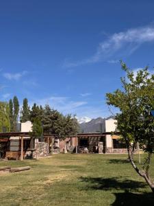 Cabañas del Pasaje في Las Compuertas: مبنى في حقل مع شجرة في المقدمة