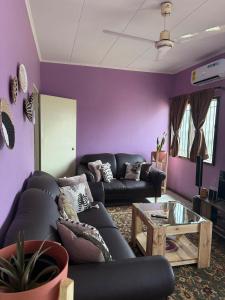 Una sala de estar con paredes moradas y sofás negros. en East Legon Self-Contained Unit, Greater Accra, en Accra