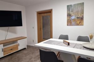 a dining room with a table and a flat screen tv at Ferienhaus am Mühlgrundbach in Schöna
