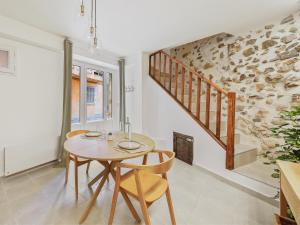 una sala da pranzo con tavolo, sedie e scale di L'Evasion Tropicale - idéal couple - sauna - baignoire balnéo LED - TV 4K Ambilight 130cm - parking gratuit à 2 pas du logement - wifi - maison médiévale sur 2 étages - entièrement rénovée 37m2 a Bargemon