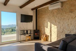 een woonkamer met een tv en een stenen muur bij Green House Zêzere 