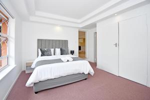 een witte slaapkamer met een groot bed en een raam bij Sandton Elite Stay in Sandton