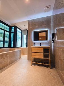 baño grande con TV y bañera en The Green Hall, en George Town