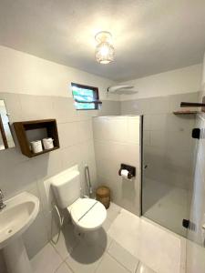 a bathroom with a toilet and a shower and a sink at Pousada Lumawê Caraíva in Caraíva