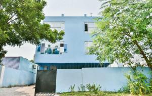 ein blaues Gebäude hinter einem Zaun und Bäumen in der Unterkunft Hotel O AG Colony Park Patna Formerly Capital Pearl in Patna