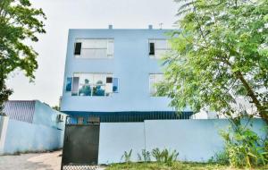 ein blaues Gebäude hinter einem Zaun und Bäumen in der Unterkunft Hotel O AG Colony Park Patna Formerly Capital Pearl in Patna + 72 Fotos