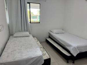 zwei Betten in einem kleinen Zimmer mit Fenster in der Unterkunft Vila Bella Residence in Gravatá + 5 Fotos
