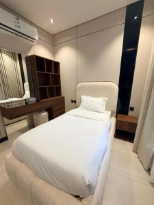 a bedroom with a large white bed and a bathroom at Excellence Apartment شقه التميز في المونسيه in Riyadh