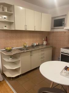 a kitchen with white cabinets and a white table at Roza in Ruma