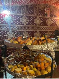 two trays of different types of food on a table at Wadi Rum Bedoun in Wadi Rum