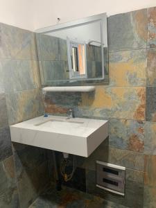 een badkamer met een witte wastafel en een spiegel bij Belvys Home in Kribi