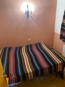 un letto con una coperta a righe colorate su una parete di Casa Alta 14 B a Palanques Altre 2 foto